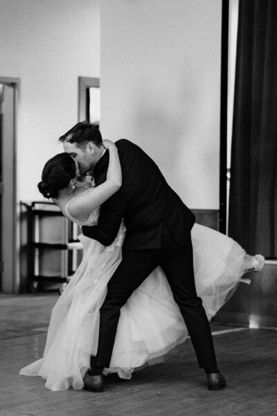 A kiss and dip performed by the bride and groom, in black and white