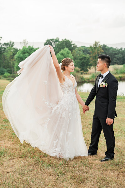 A bride holding up the end of her dress with one hand and her partner's hand in the other