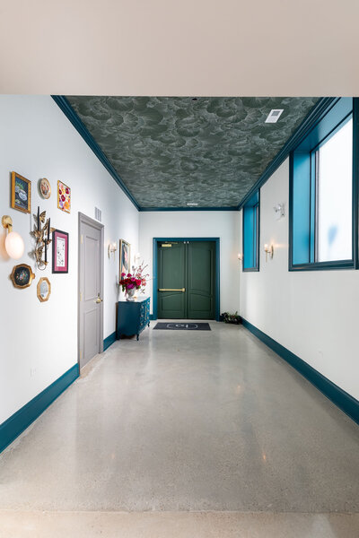 entryway of venue, introducing her personality with blend of hand-picked antique and custom made art pieces, furniture, sconces and color