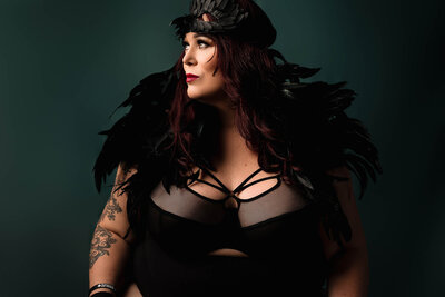 With feathers and long hair a woman poses for a boudoir photographer in Vancouver