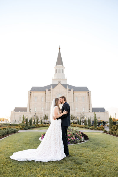 Newly married couple share a loving kiss in front of the Taylorsville LDS temple.