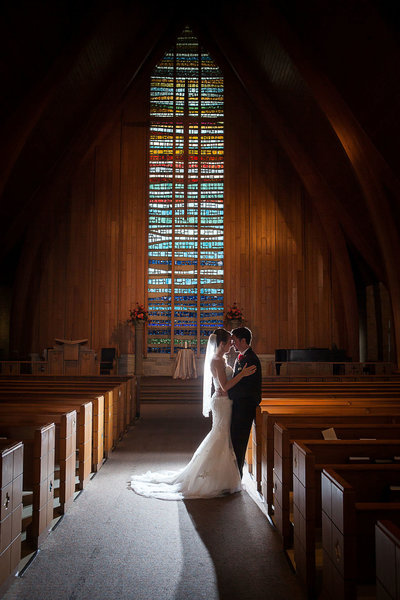 Couple silhouette in aisle with stained glass in Caldwell Chapel after wedding in Kentucky