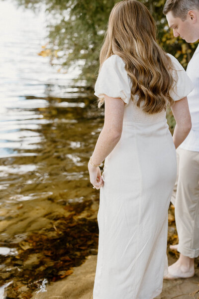Ottawa engagement photographer captures candid lakeside moment of couple walking barefoot during golden hour session.