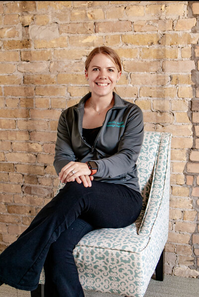 owner Kayla Stroud-DuSavage smiling in front of massage table - Massage Therapy in Sun Prairie WI Specific Health Massage Therapy