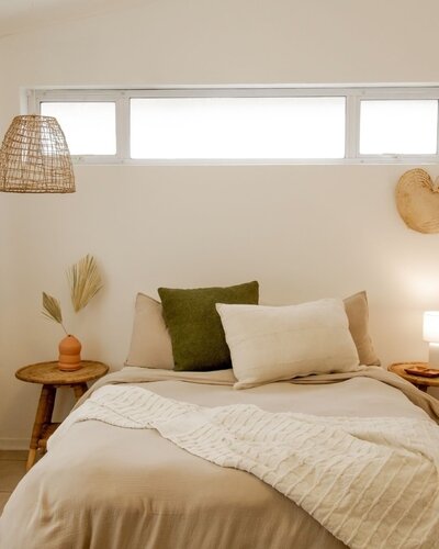 Minimalist bedroom inspiration featuring neutral bedding, natural textures, and a woven pendant light.