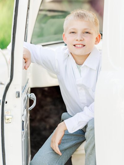 Son smiling and sitting in a vintage truck outside.