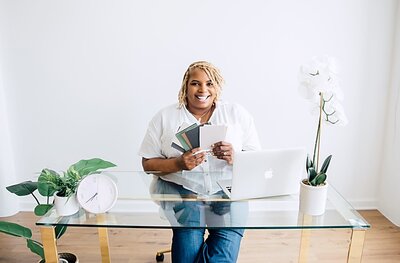 black lady on sitting on couch with laptop