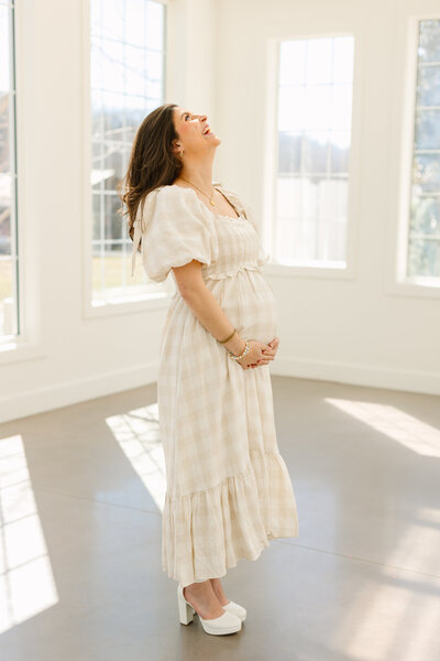 Pregnant mama holds growing pregnant belly at the beautiful luxe glass house for her Asheville Maternity Session with Asheville Maternity Photographer Rachel Marie Photography