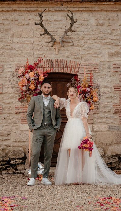 Juste après leur cérémonie laïque au Château de Vaux en Champagne, les mariés posent face caméra devant l’arche – un moment fort et élégant capturé par un duo photographe vidéaste