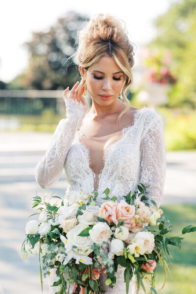Bride in wedding dress on her wedding day holding a blush bouquet.