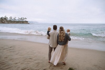 male and female walking at laguna beach with two small children