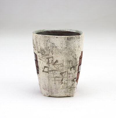 A ceramic cup that resembles plaster falling apart from red bricks with painted cacti and graffiti
