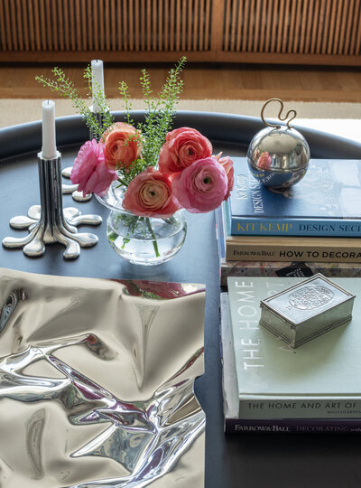 Närbild på designböcker, silverdetaljer och ranunkel – detaljer från Caspar & Co:s vardagsrumsstyling