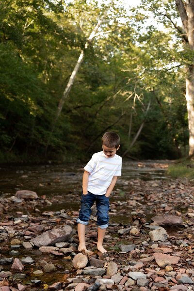 Boy in a white shirt standing in a creek