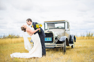 Bride and groom laughing at outdoor session with antique car