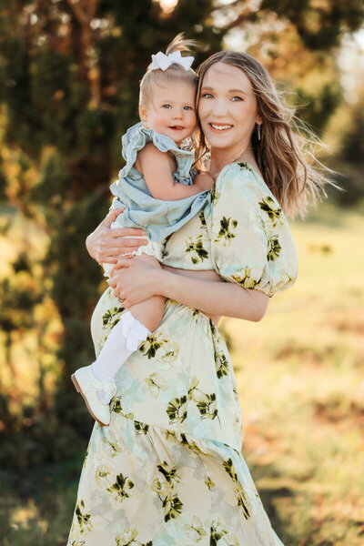 Expecting mom holding toddler during a maternity session in Sedona, Arizona in a floral dress.