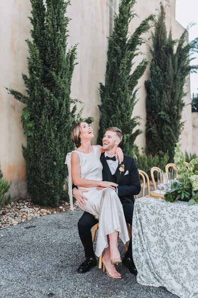 bride sitting on groom's lap during reception