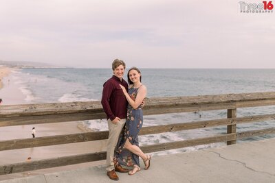 Engaged couple pose together on the Balboa Pier in Newport Beach