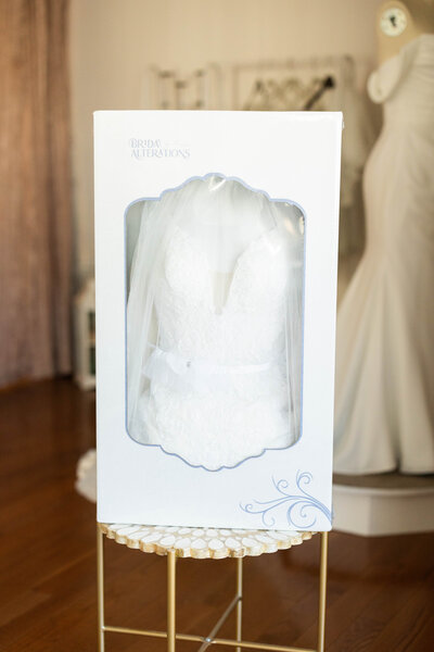 Wedding dress hanging in front of a window, casting a shadow in a well-lit room