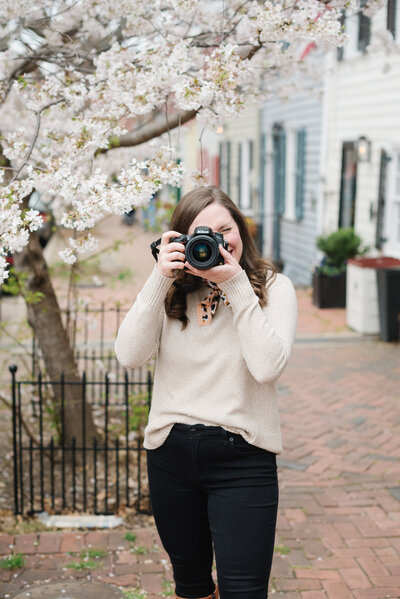 Photographer holding camera with cherry blossoms in background - Washington DC Family Photographer