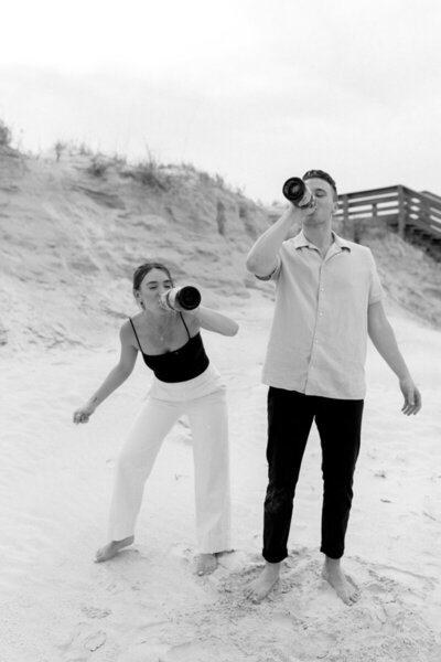 Couple drinking from bottles on the beach for session with Orlando engagement photographer, Marissa Nicole