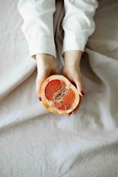 A person holding a freshly cut grapefruit, symbolizing mindful eating, nourishment, and vibrant health.