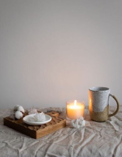 Candle and mug on top of an off-white fabric