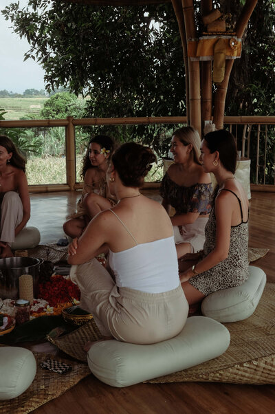 A women holding up a bowl and meditating in a Bali setting.