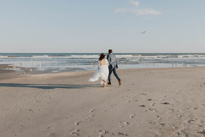 newlyweds run on beach