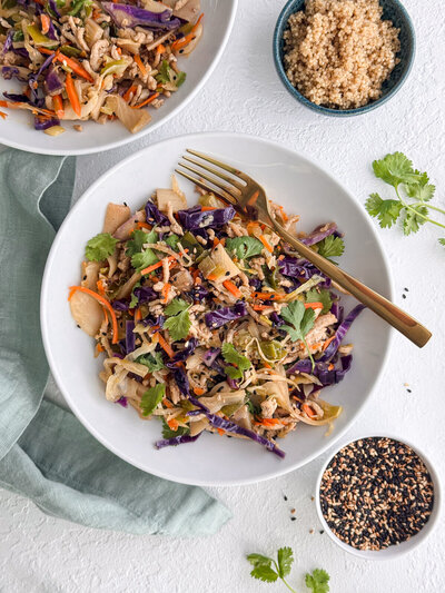Turkey egg roll in a bowl with a purple cabbage, shredded carrots, fresh cilantro, bamboo shoots and topped with sesame seeds.