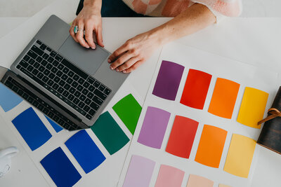 Beth Requist, Winter Park custom web designer, overview of hands working on a computer at a desk with color swatches next to it