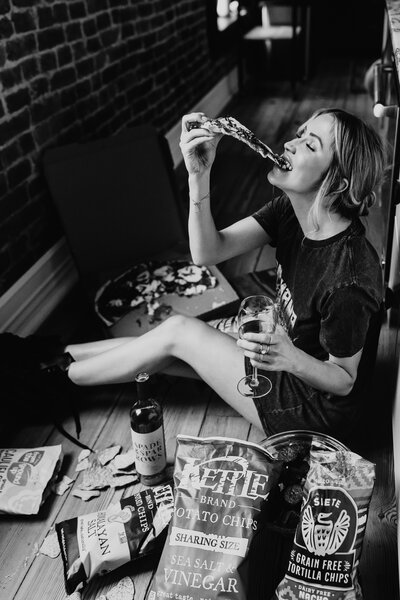 woman eating pizza and snacks, drinking wine