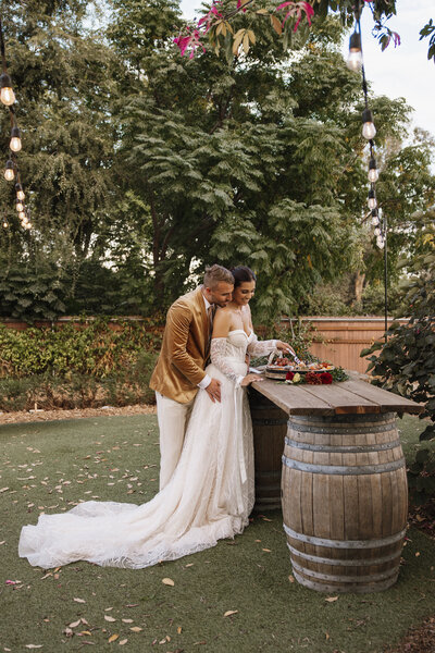 Bride and groom sharing a kiss in a beautifully decorated Los Angeles garden, surrounded by lush greenery and blooming flowers during their wedding ceremony
