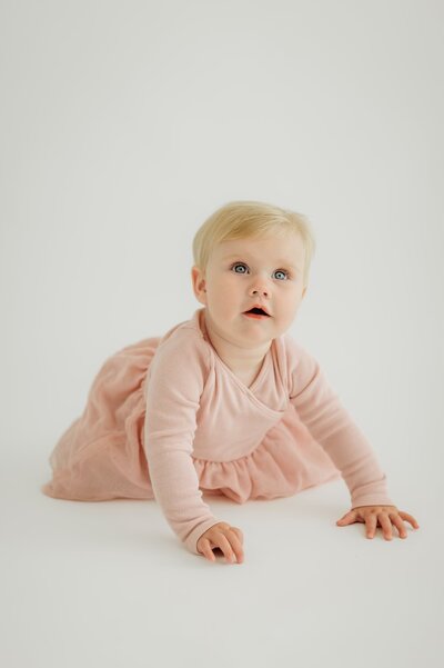 baby crawling and looking above camera for her studio portrait photo session