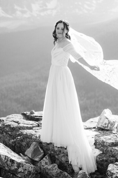 Capture the joy of a bride playing with her dress on a warm summer day atop a mountain by Moraine Lake. A stunning moment of happiness and natural beauty on her wedding day.
