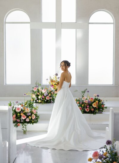 Bride and groom sharing a kiss surrounded by cheering bridal party.