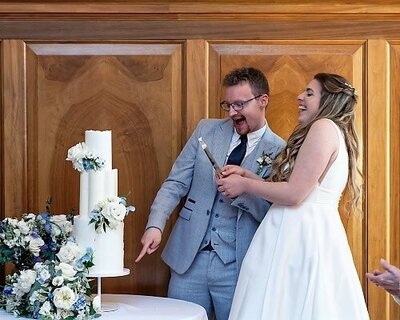bride and groom cutting their wedding cake and laughing out loud