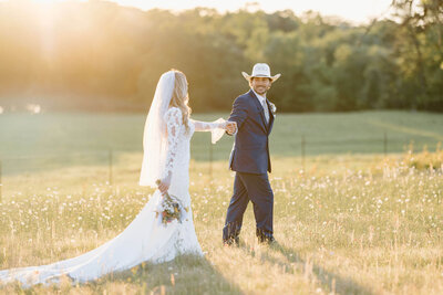 wedding day portrait of groom in navy suit and straw cowboy hat kissing bride on long sleeved lace white wedding gown after Hallsville, TX wedding ceremony