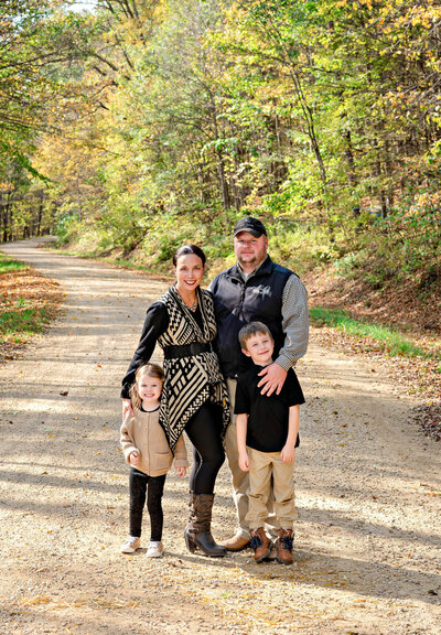 family of mom and dad with 2 kids on a dirt road in the fall