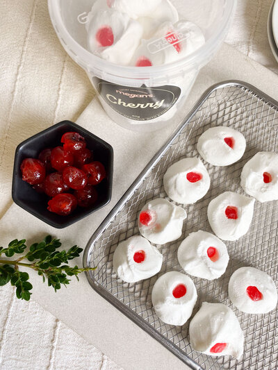 White hand piped meringues with bright red tip.