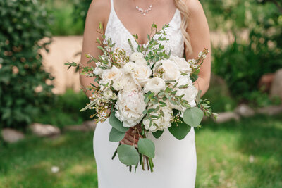 Bride holding a lush floral bouquet, showcasing elegant wedding details and soft colors
