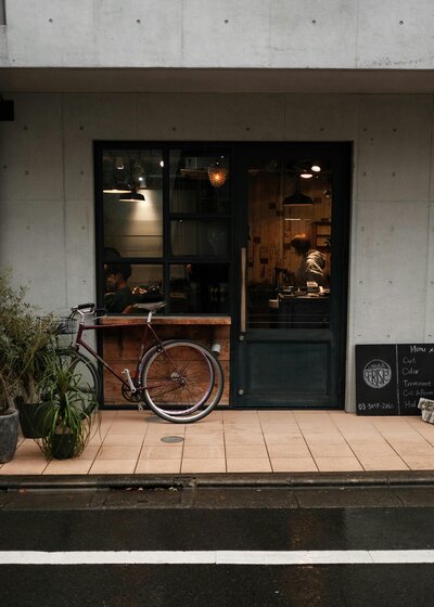 Exterior of a cozy café in Tokyo with a bicycle parked outside and warm lights glowing inside