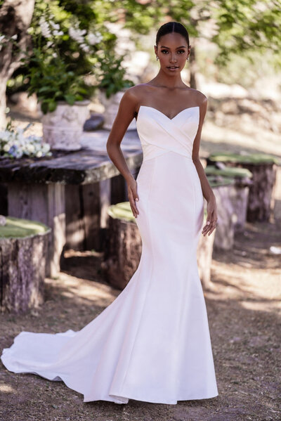 Bride wearing a simple strapless fitted wedding gown in an outdoor garden setting