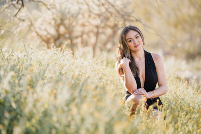 Senior girl sitting on a short wall, in a tulle dress and necklace