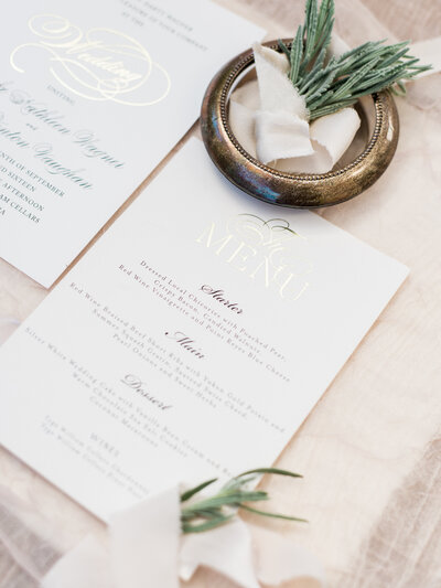 Wedding dinner menu with gold napkin ring and greenery