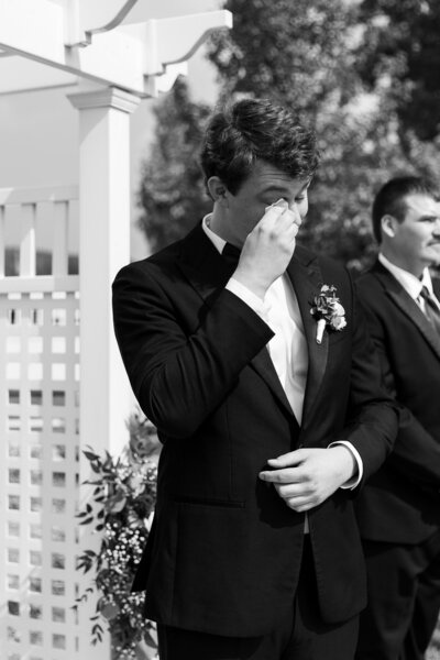 groom crying as his bride walks down the aisle at wedding on Gun Lake