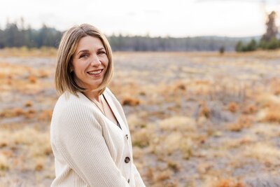 femal wedding photographer posing with camera in the mountains