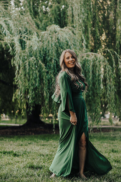 Patty in a green dress outside in front of a tree
