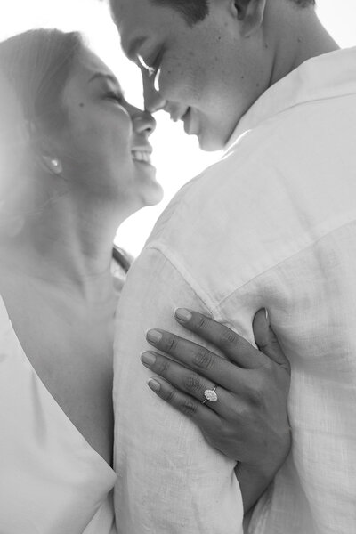 Black and white photo of bride and groom smiling with wedding ring