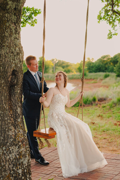 groom pushing bride on swing at oklahoma wedding